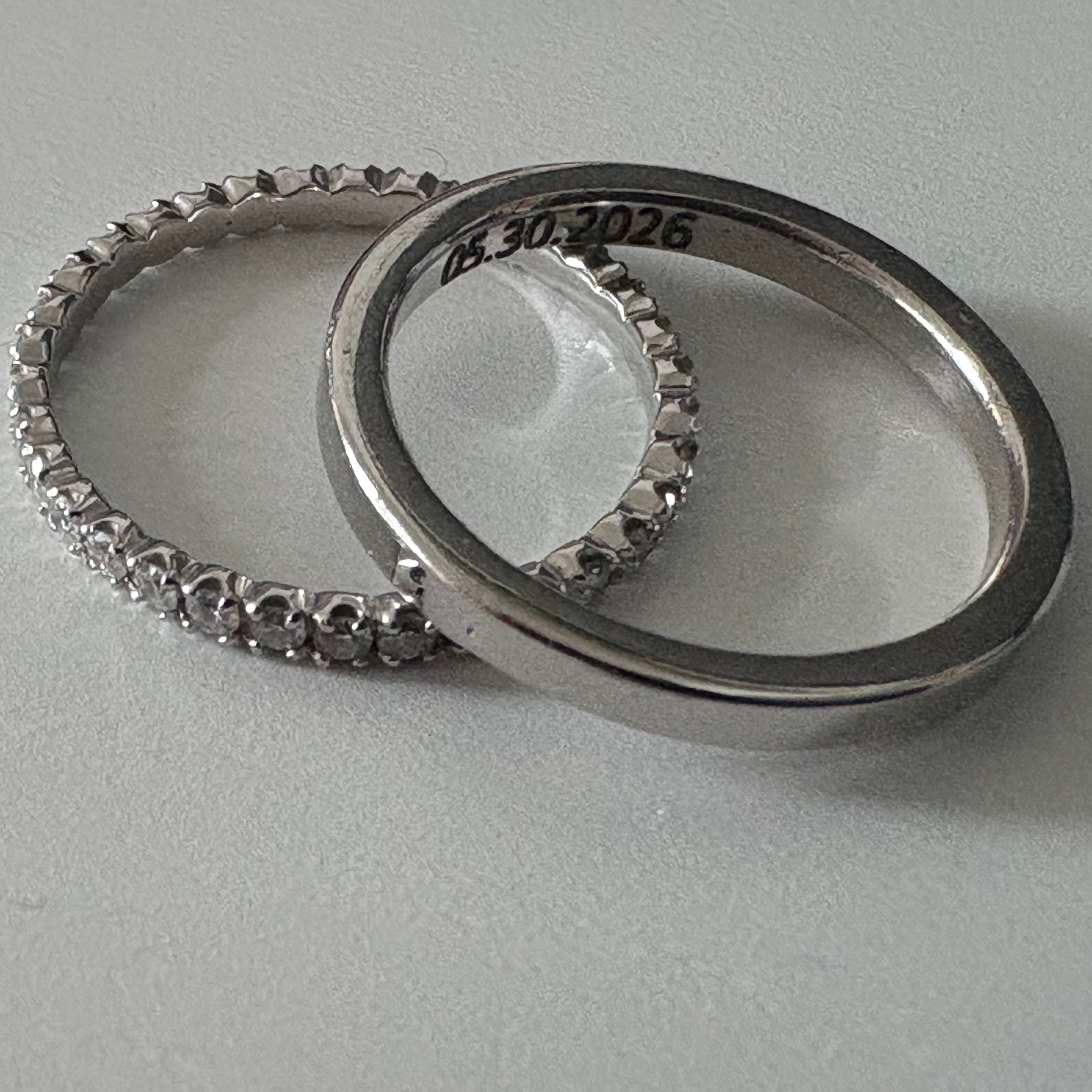 Two silver rings with engraved dates on a light gray background