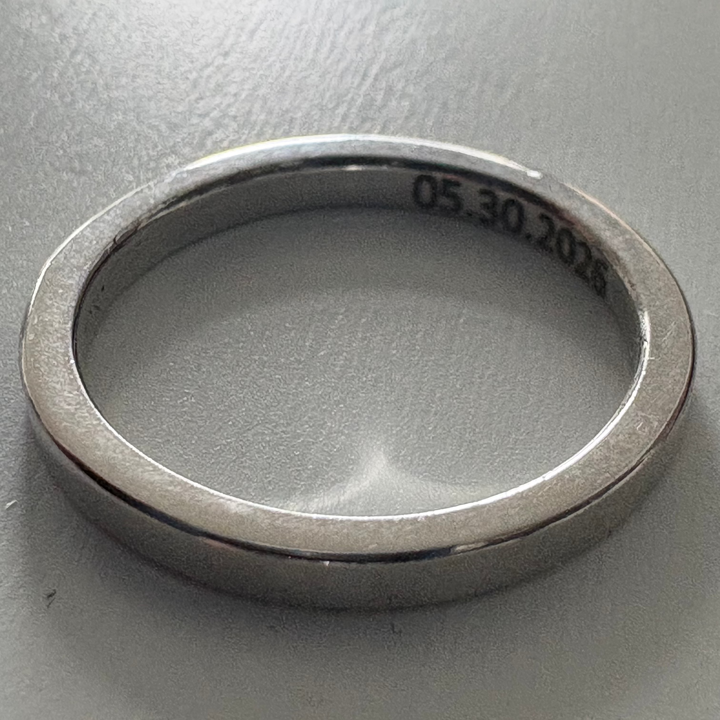 Silver ring with engraved date on a gray background